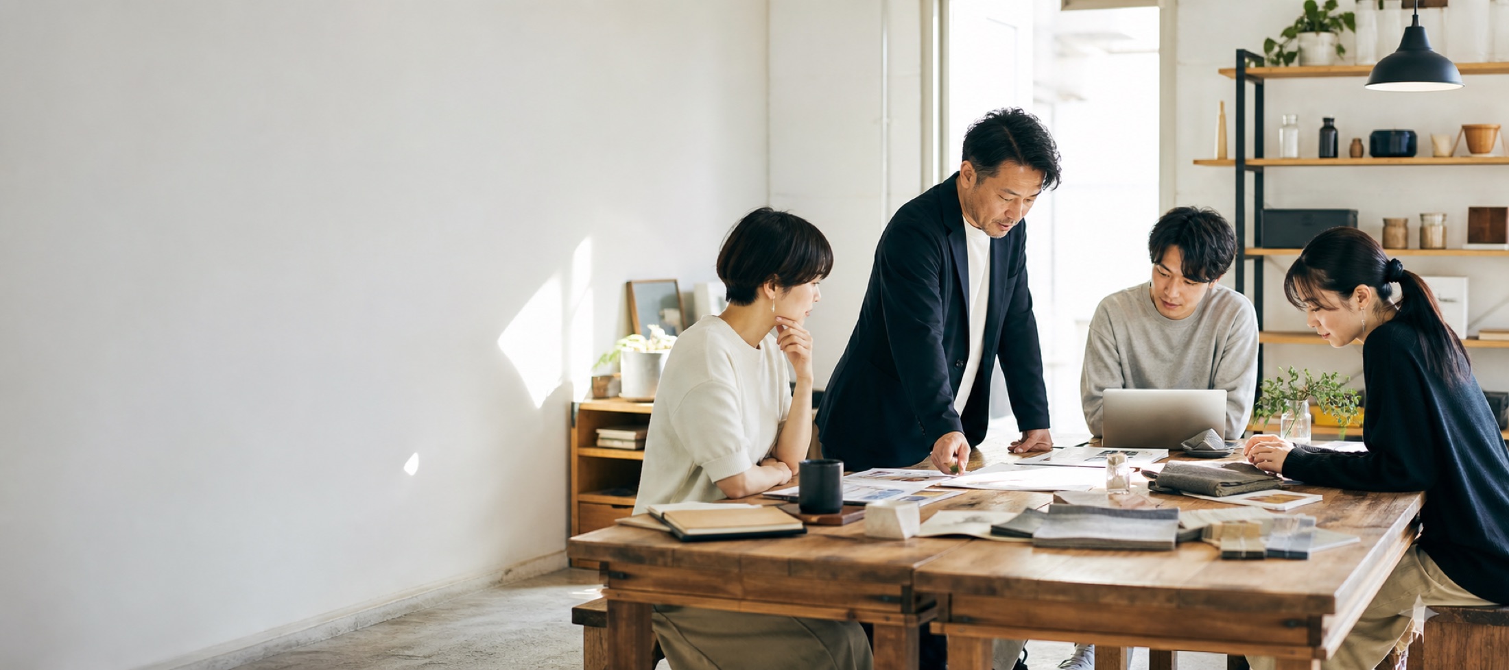 社長とチームが机を囲み、事業の資料を見ながら話し合っている様子